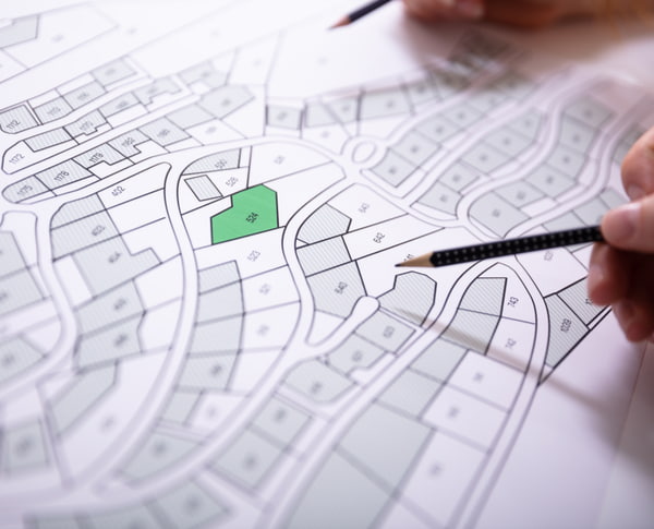 Human hand holding pencil over paper cadastre map